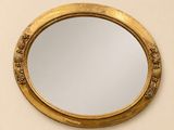 une image représentant un miroir rond accroché au mur, avec un cadre doré