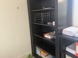 a black bookcase with many books on it in a room