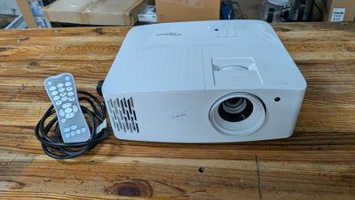 une photo d'un projecteur posé sur une table en bois, à côté d'une télécommande