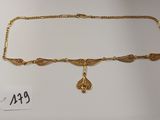 gros plan d'un collier en or sur fond blanc