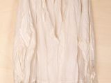 white blouse hanging on a hanger on a wooden wall