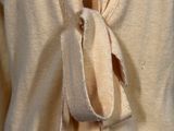 a woman wearing a tan cardigan with a tie around her neck