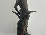 bronze statue of a man with a sword and a hat on a black base