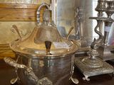 a silver bowl with a lid on a table next to a mirror
