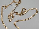 a gold chain with a tag attached to it on a gray surface