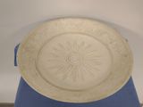 a white plate with a sun design on it on a blue table