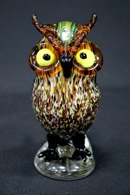 une figurine de chouette posée sur un socle en verre