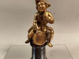 figurine en laiton représentant un garçon assis sur un tuyau