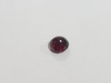 a close up of a red garnet stone on a white surface