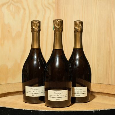three bottles of wine sitting on top of a wooden barrel