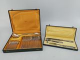 deux sets d'argenterie dans un coffret sur une table