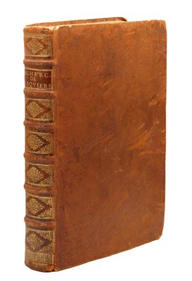 un vieux livre à la couverture brune posé sur une surface blanche