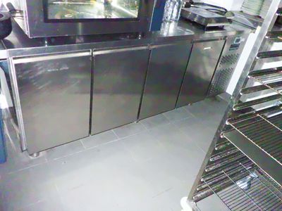 une cuisine équipée d'armoires en inox, sur lesquelles est posée une télévision