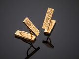 a pair of gold cufflinks on a black surface