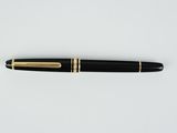 un stylo noir et or posé sur une surface blanche