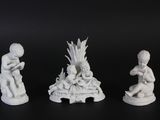 trois figurines blanches représentant des enfants assis sur une surface noire