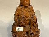 une petite statue en bois représentant une femme assise sur une fleur