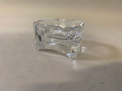 un petit objet en verre posé sur une table, sur fond blanc