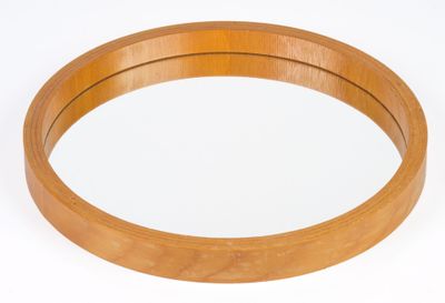 a round mirror with a wooden frame on a white surface