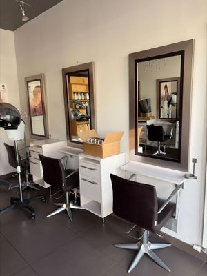 une photo d'un salon de coiffure avec des fauteuils et des miroirs