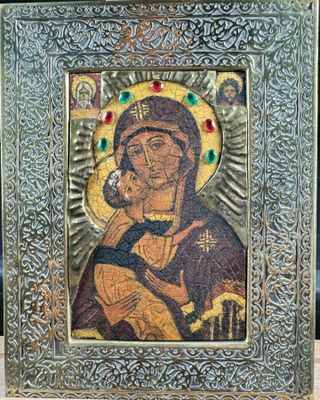 the icon of the mother of jesus is displayed in a silver frame