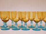 six verres à vin bleus et jaunes sont alignés sur une surface blanche