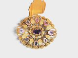 gold tone brooch with multi colored stones on a white background