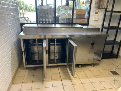 un plan de travail en acier inoxydable dans une cuisine professionnelle, doté d'une porte vitrée