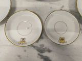four white and gold china plates and bowls on a marble surface