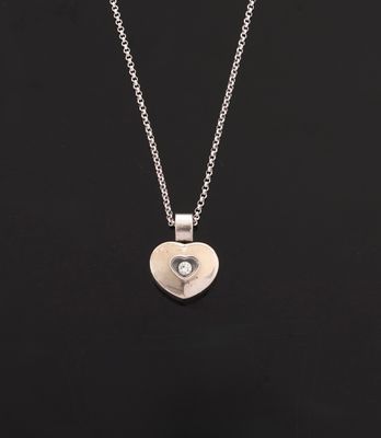 a silver heart shaped pendant with a diamond on a chain