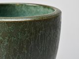 a close up of a green bowl on a white surface