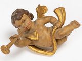 une statue représentant un petit garçon allongé par terre, tenant une trompette