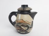 a black and white tea pot with a mountain scene on it
