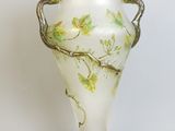un vase blanc orné d'un motif vert et doré
