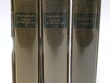 Trois livres sont alignés sur une surface blanche ; l'un est noir et l'autre est doré.