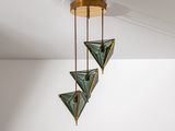 un gros plan sur un plafonnier composé de trois triangles en verre vert suspendus au plafond
