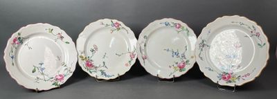 quatre assiettes ornées de motifs floraux sont alignées sur une surface noire