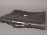 a brown briefcase sitting on a table with a gray background