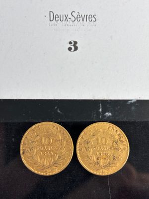 two gold coins in a box on a black surface