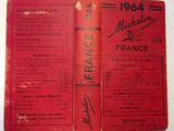 an old book with a red cover sitting on top of a table