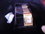 a gold watch sitting in a velvet case with a piece of paper