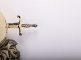 a silver vase with a sword on top of it
