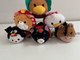 cinq peluches assises côte à côte sur une surface blanche