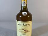 Des bouteilles de vin sont posées sur une table devant un fond blanc.