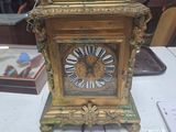 une horloge en or posée sur une table, avec une étiquette indiquant son prix