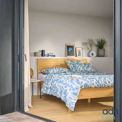 un lit dans une chambre, avec une tête de lit en bois et une couette bleue