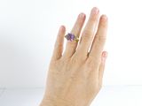 a woman ' s hand holding a purple flower ring