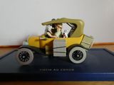 une petite voiture jaune avec un homme à l'intérieur, posée sur un plateau bleu