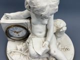 a small statue of a boy sitting on a clock