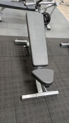 a gym with a bench and weights in the middle of the room